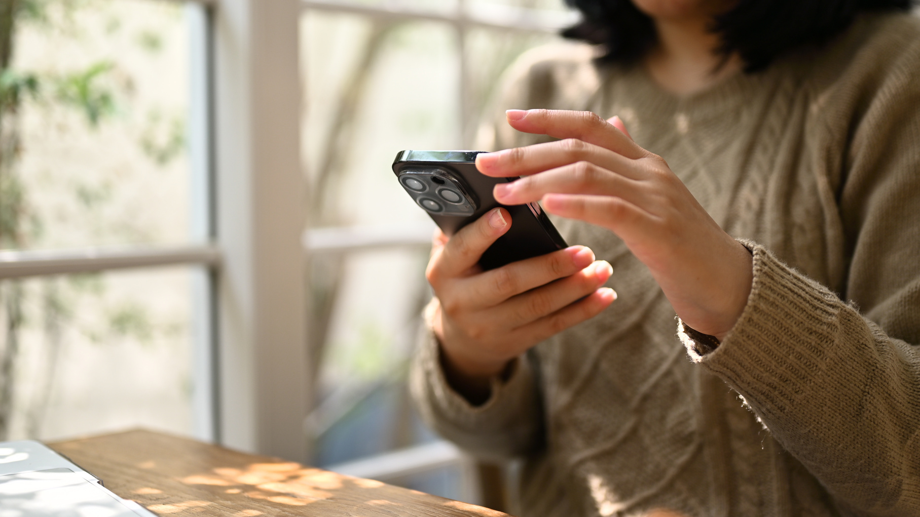 A woman using her smartphone, scrolling on her phone while relax